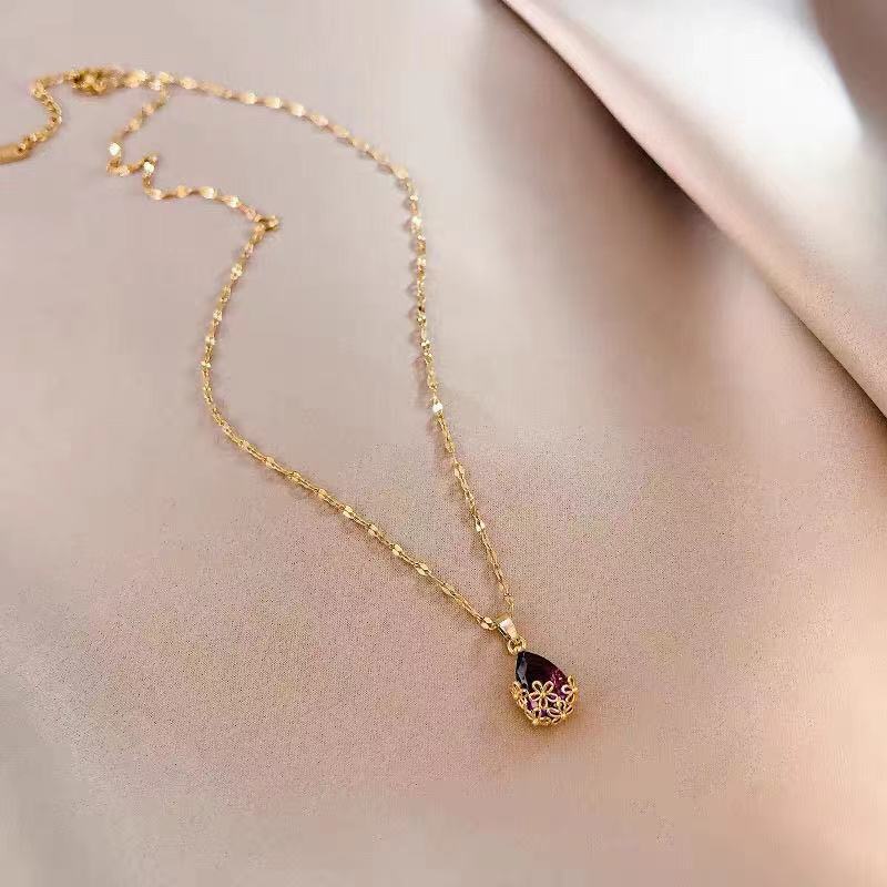 Collar largo con dije de gota de agua en piedra morada montado en flores metálicas
