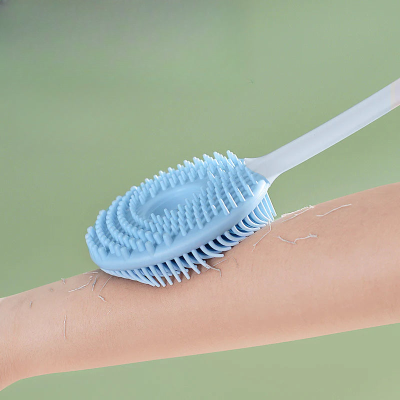 Cepillo de baño azul 2 en 1 con cerdas suaves utilizado en el brazo para exfoliar y masajear la piel durante la ducha.