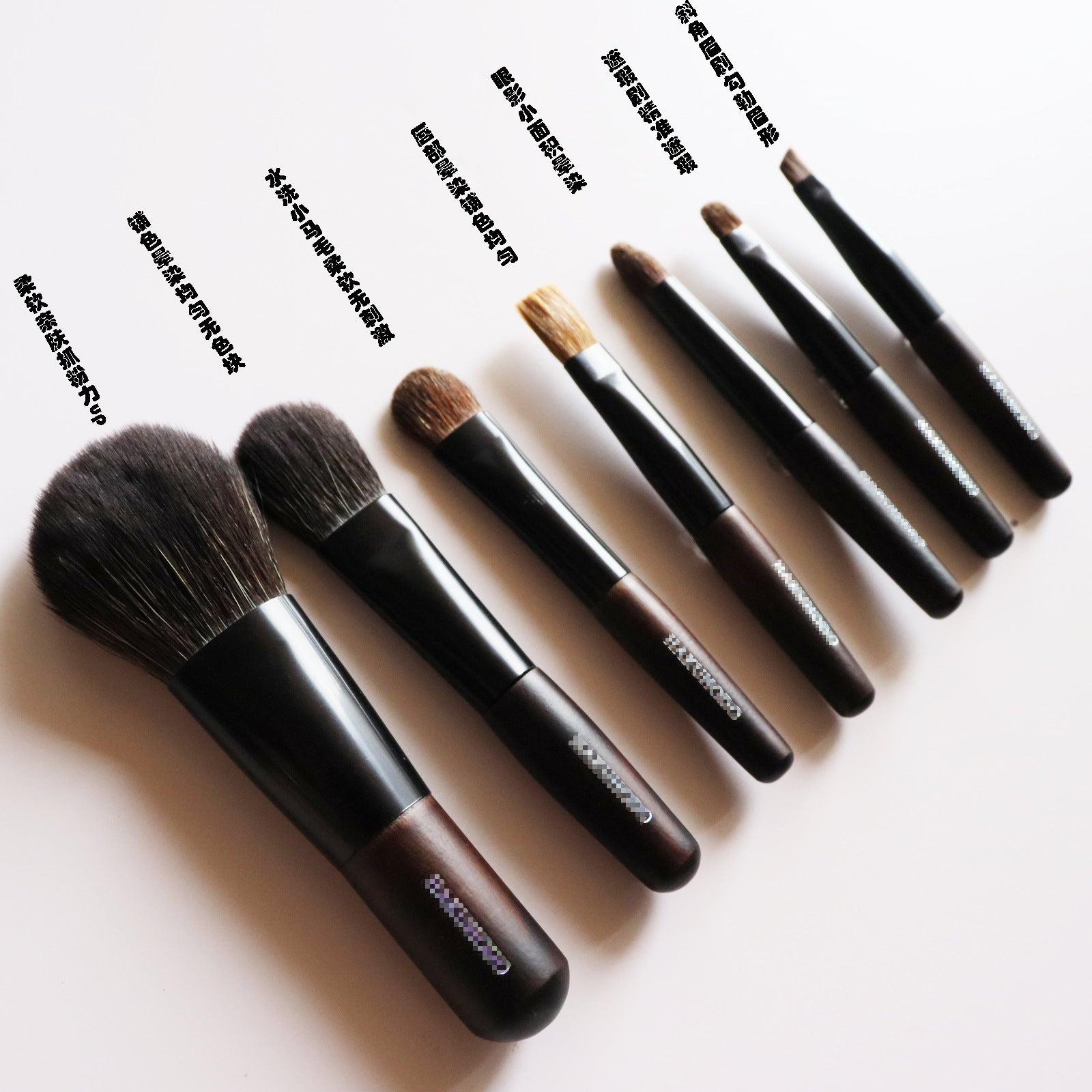 Detalle de los 7 pinceles del set de maquillaje con mango de ébano, etiquetados en chino para uso facial y de ojos.