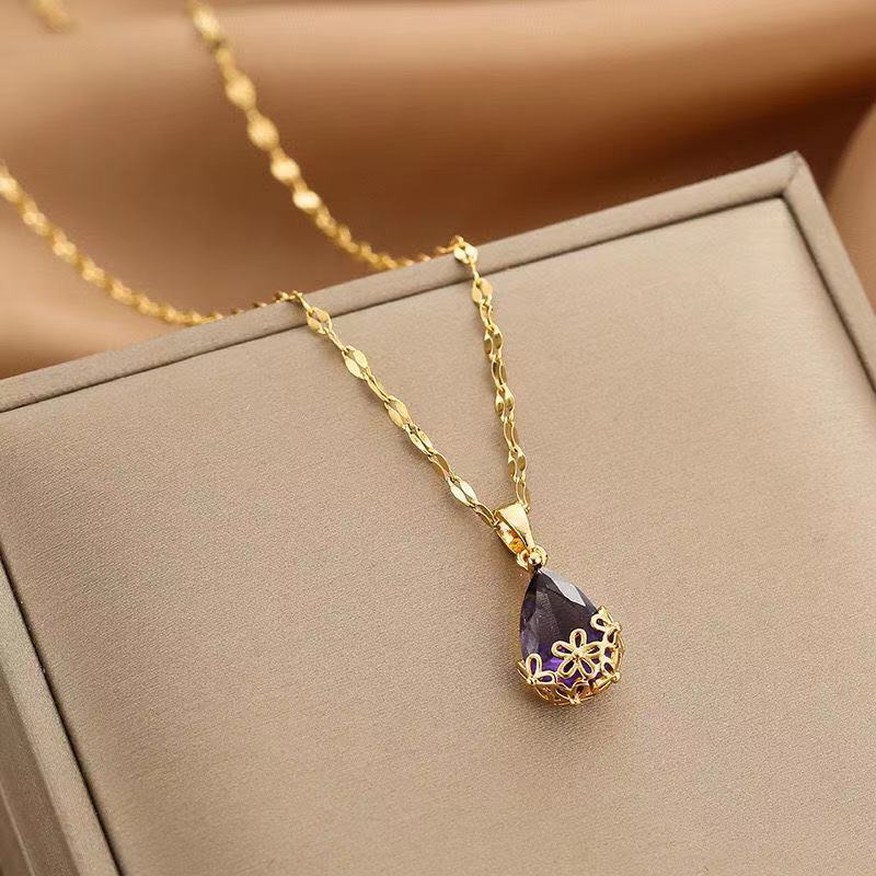 Collar largo con dije de gota de agua en piedra morada montado en flores metálicas