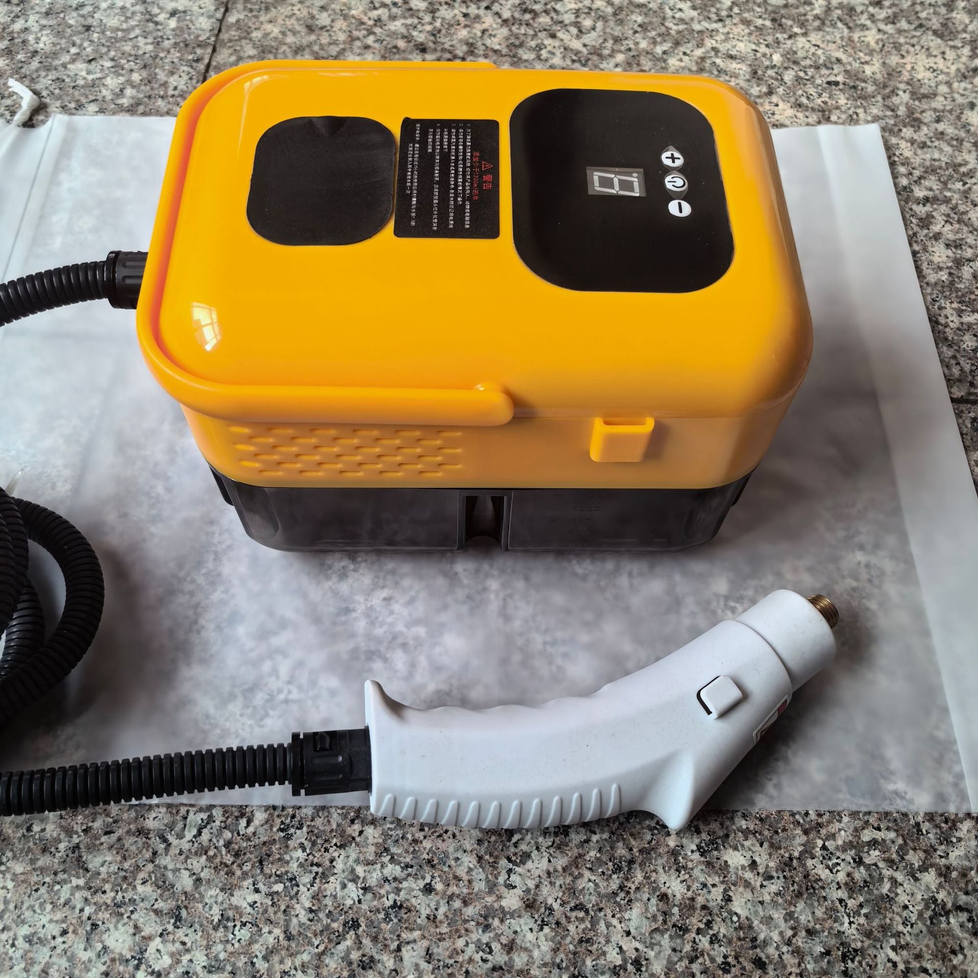 Limpiador de Vapor Portátil amarillo sobre superficie de granito. Esterilizador potente para uso doméstico en cocina y baño.