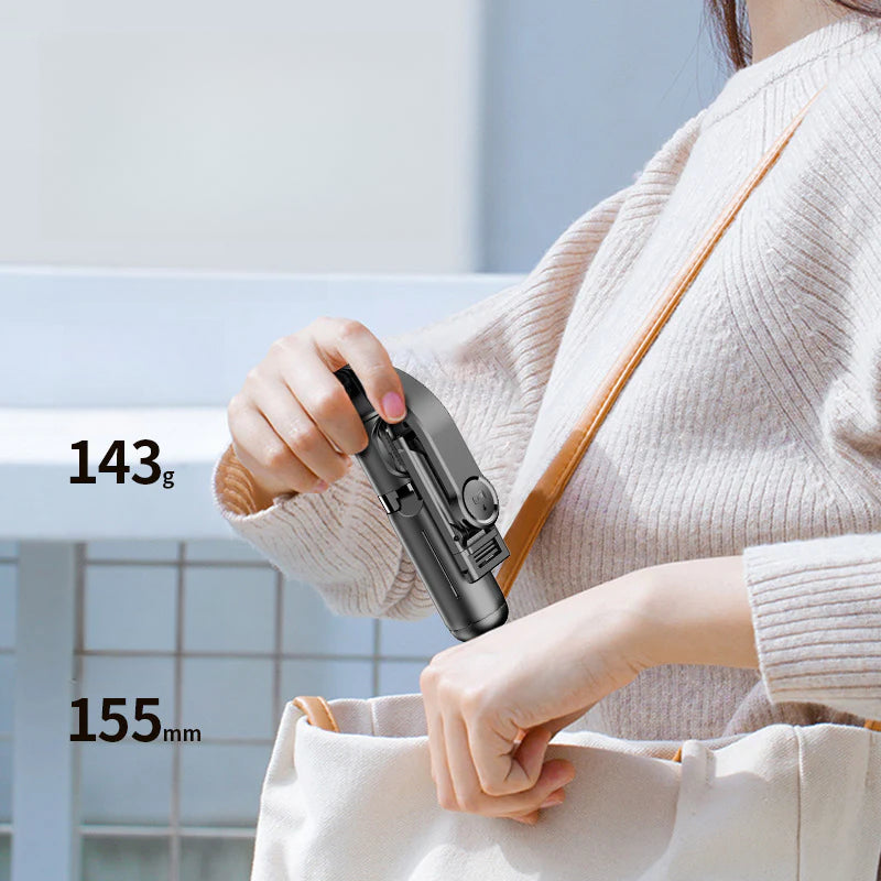 Mini Trípode Selfie Q20 con Bluetooth plegado y siendo guardado en bolso, mostrando su tamaño compacto de 155 mm y peso ligero de 143 g.